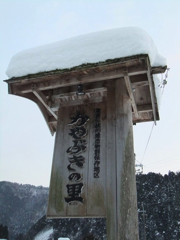 雪が積もるかやぶきの里の看板